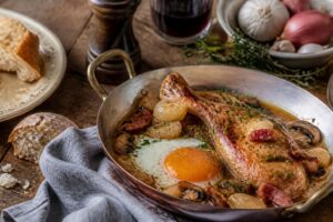 Œuf à la coque servi dans un coquetier blanc avec des mouillettes de pain grillé beurré sur une table en bois clair
